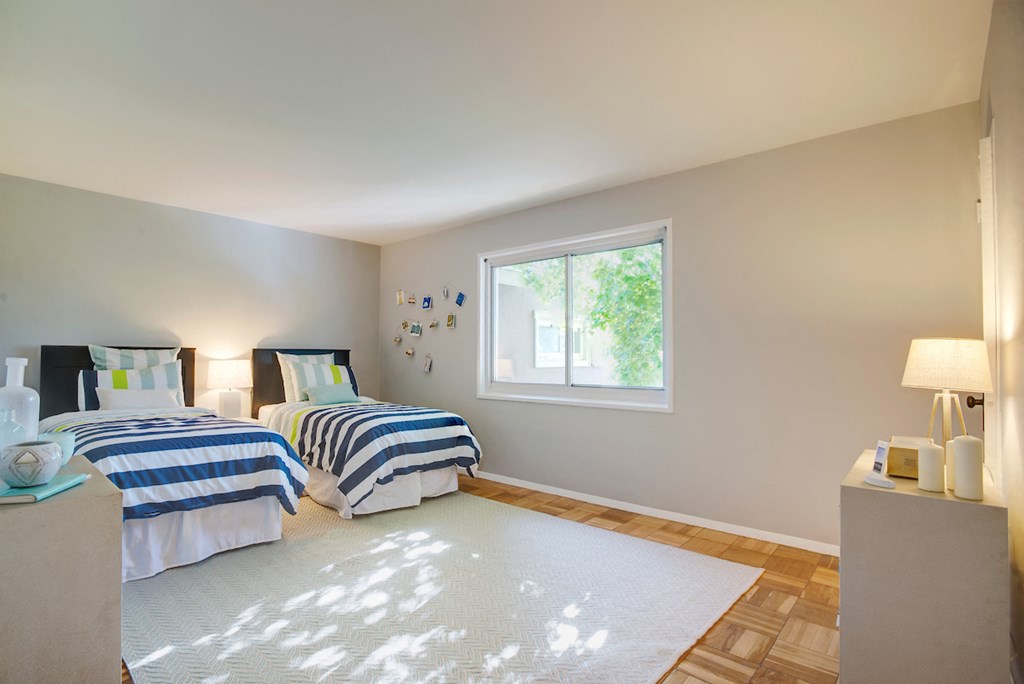 two twin beds in a bedroom with a rug and a window