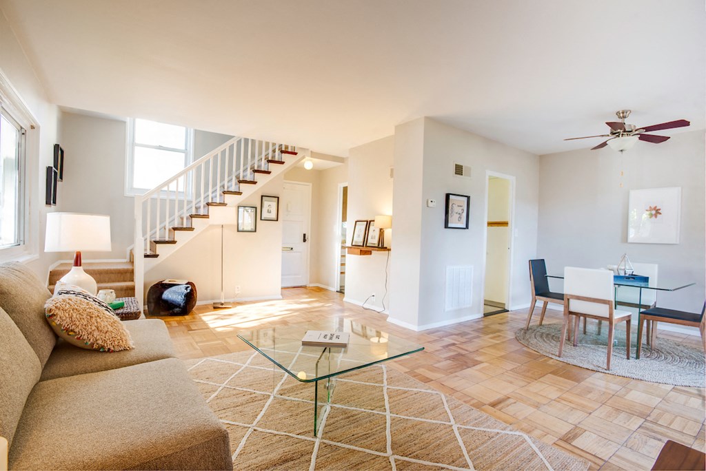 a living room with a couch and a glass table and a staircase