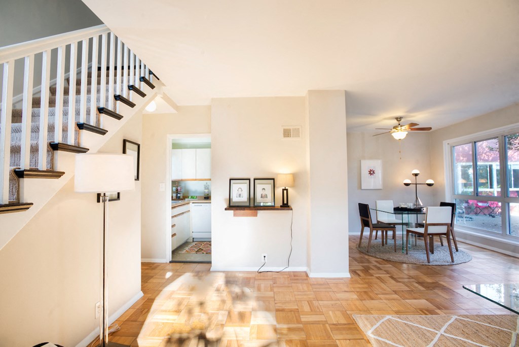 the living room and dining area of a home with a staircase and a dining table