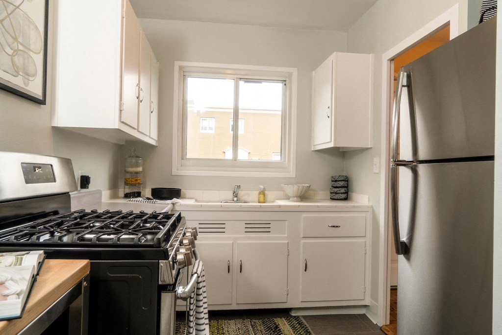 a kitchen with white cabinets and a stove and a window