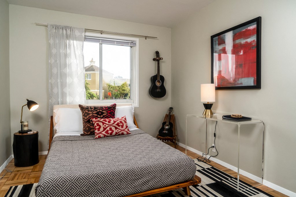 a bedroom with a bed and a guitar on the wall