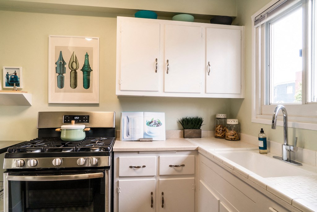 a kitchen with white cabinets and a stove and sink