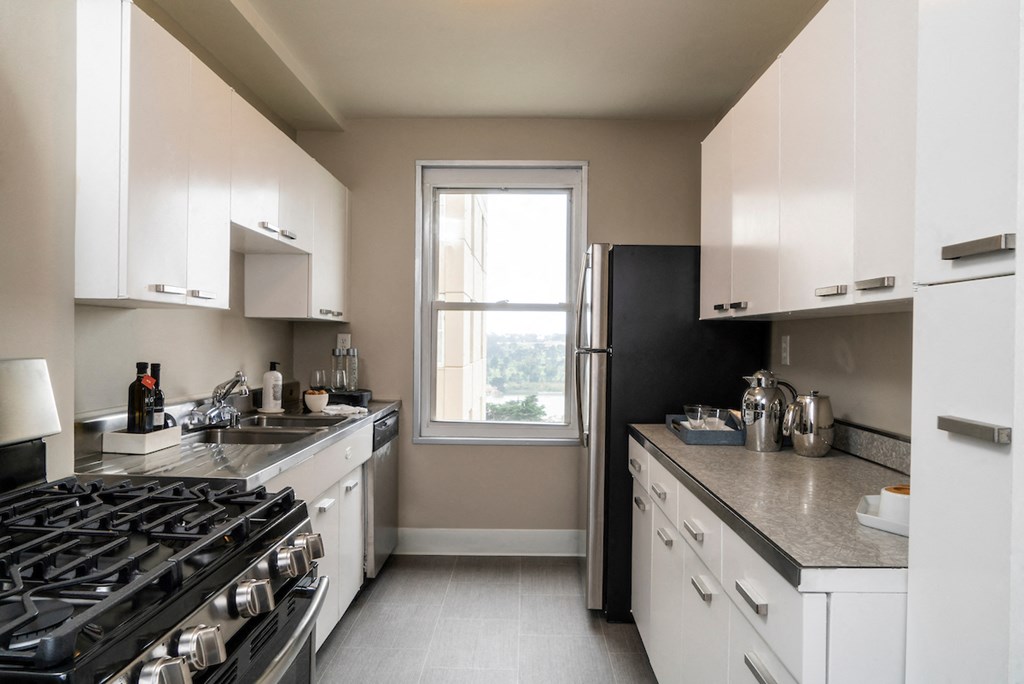 a kitchen with white cabinets and a stove and a window