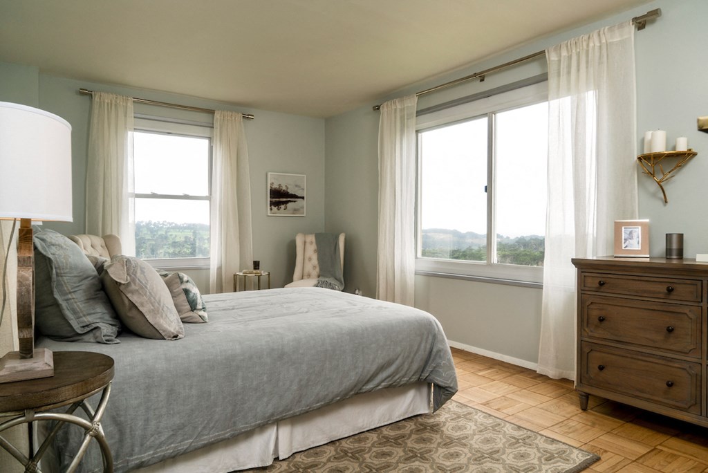 a bedroom with a bed and two windows