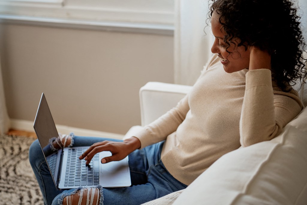 a woman sitting on a couch using a laptop computer