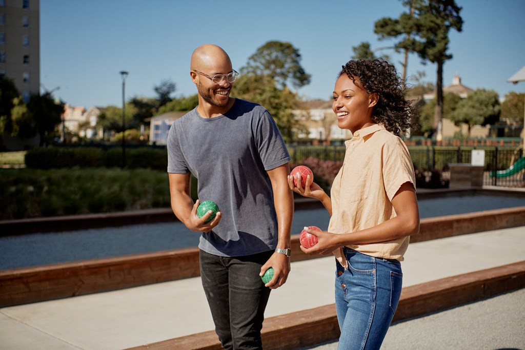 a man and a woman holding apples in a park