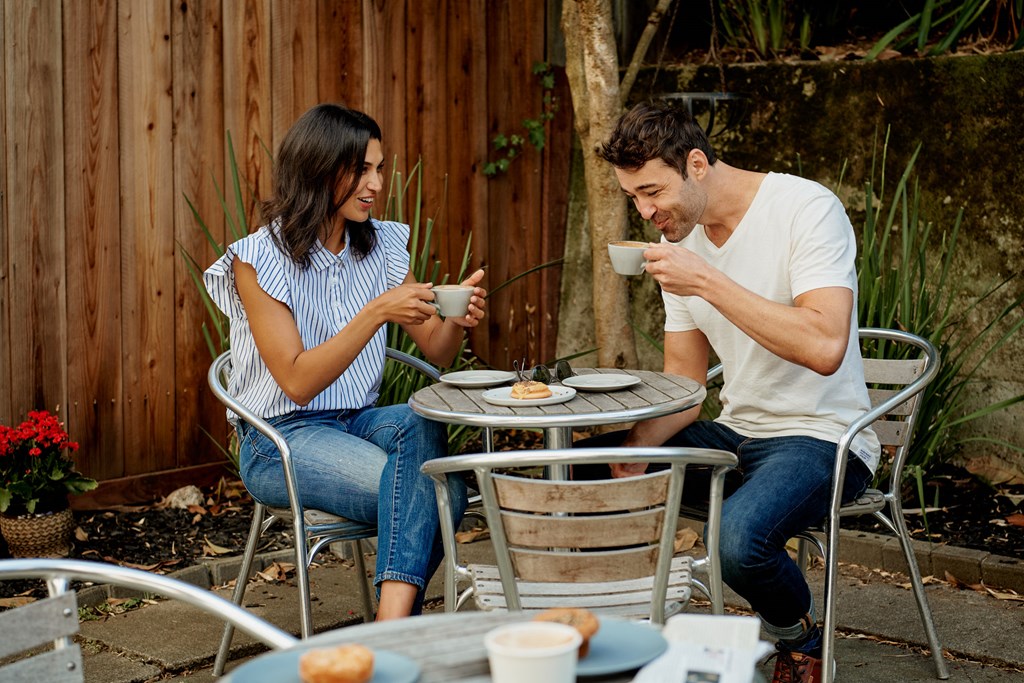 a man and woman sitting at a patio table drinking coffee