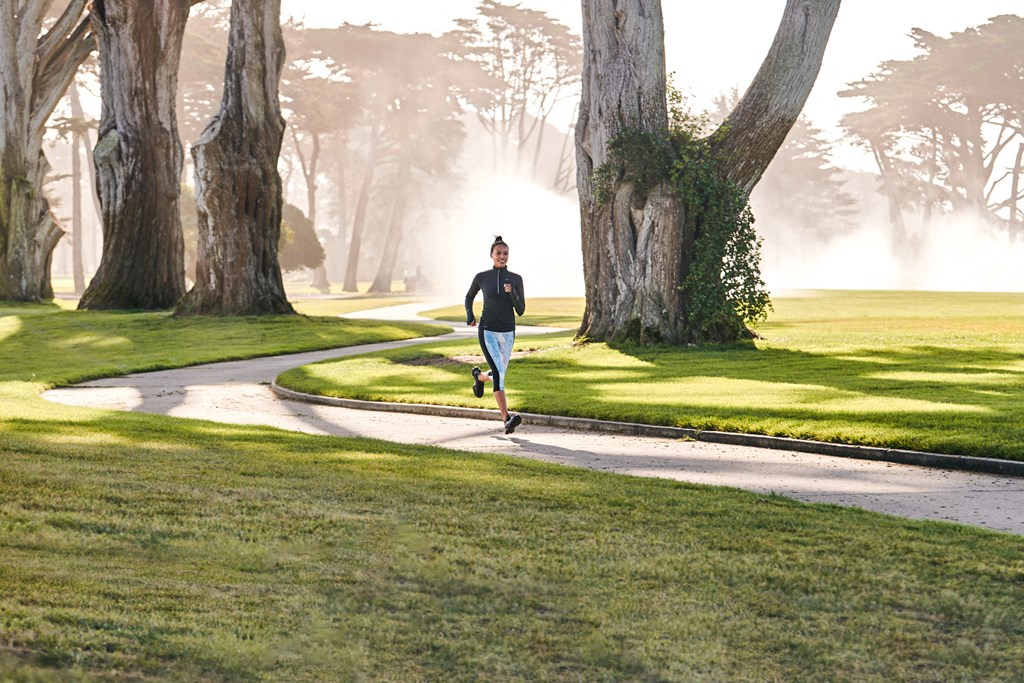 a man running down a sidewalk in a park
