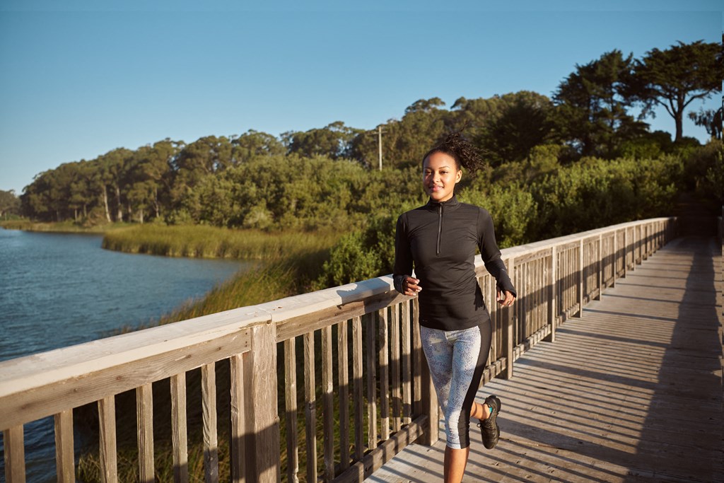 a woman running on a bridge by the water