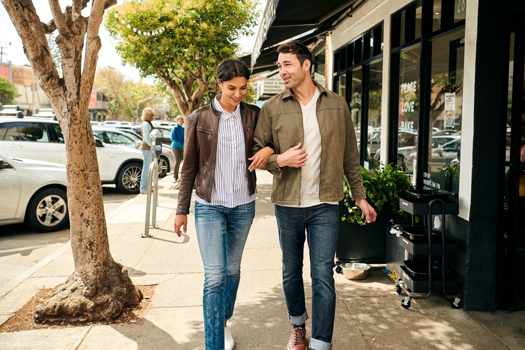 two men walking down the sidewalk in front of a store