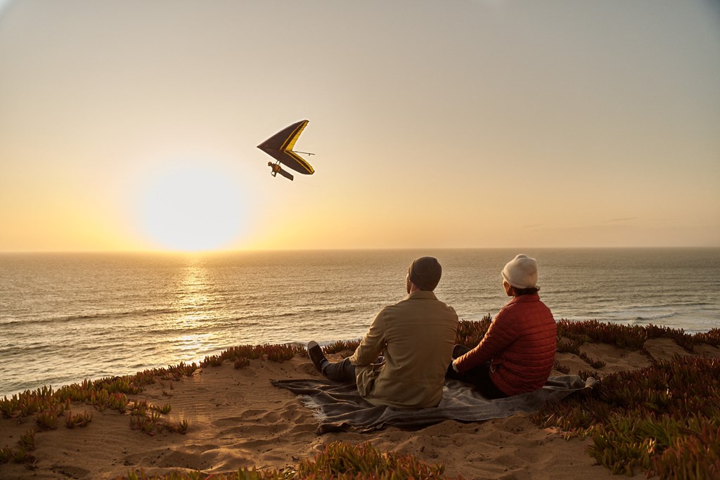 a couple flying a kite on the beach at sunset
