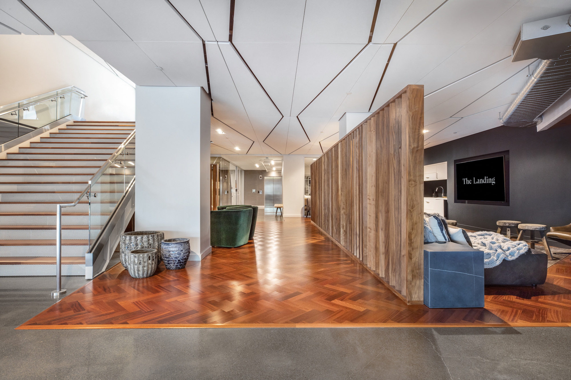 a living room with a couch and a staircase next to a wooden wall