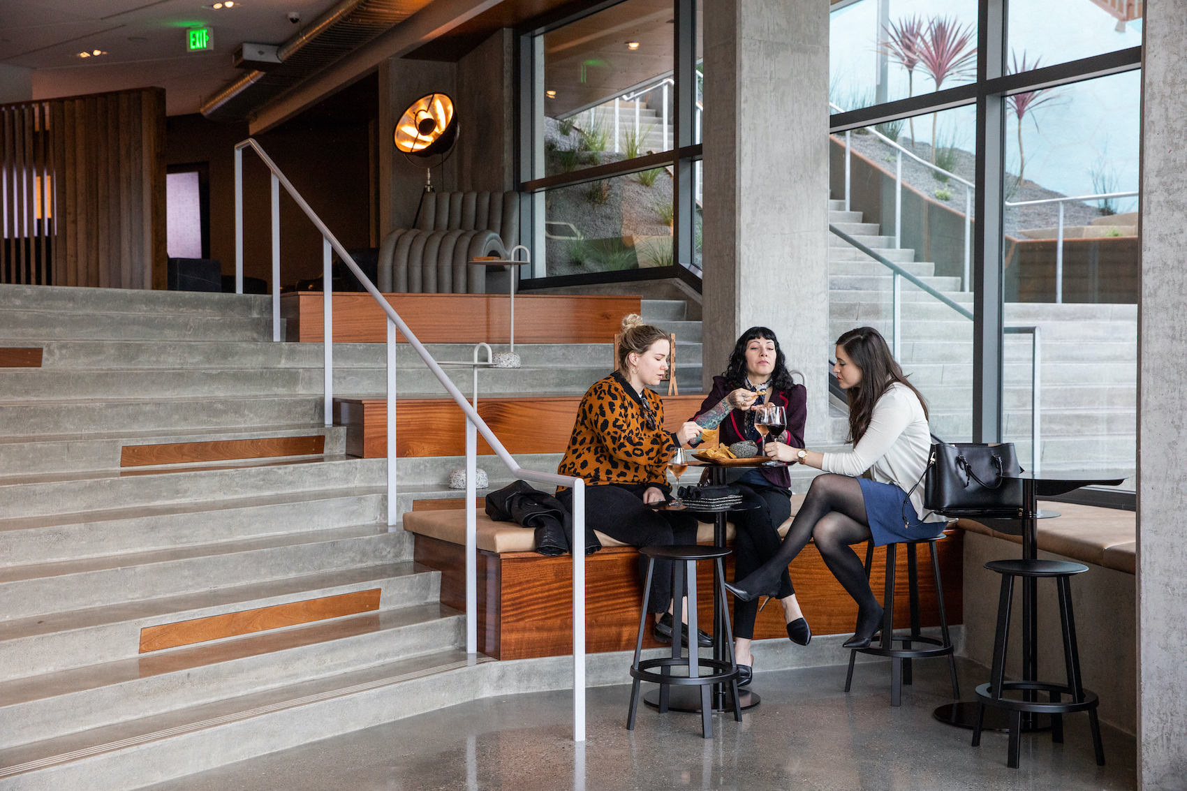 three women sitting at a table in a lobby with stairs