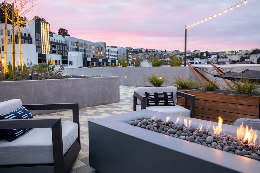 a rooftop patio with a fire pit and a city in the background