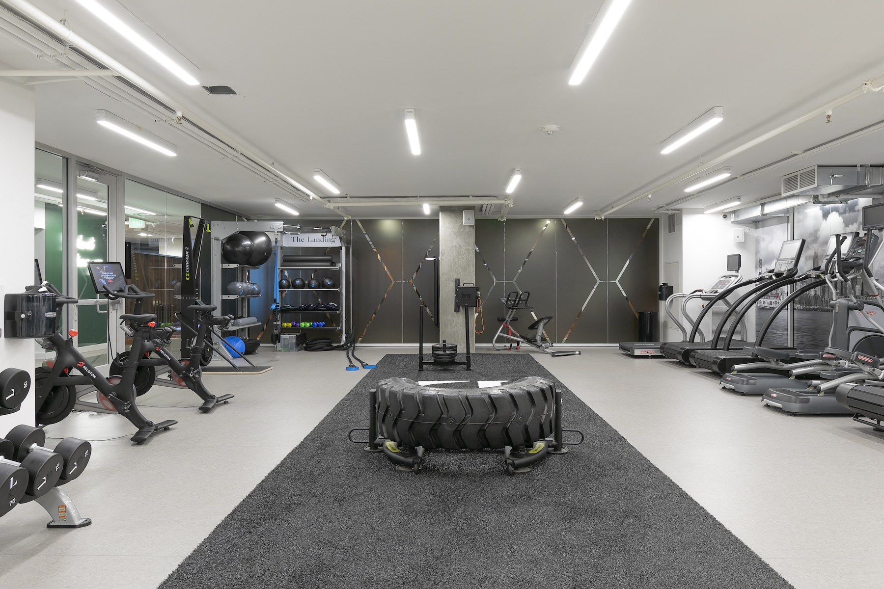 a gym with weights and cardio equipment on the floor and mirrored walls
