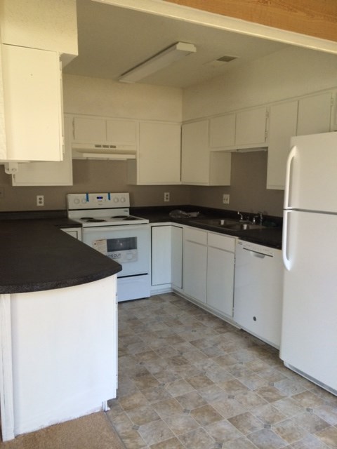 A kitchen with white cabinets and a black counter.
