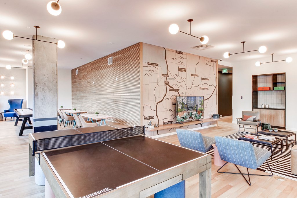 a living room with a ping pong table and a lobby with tables and chairs