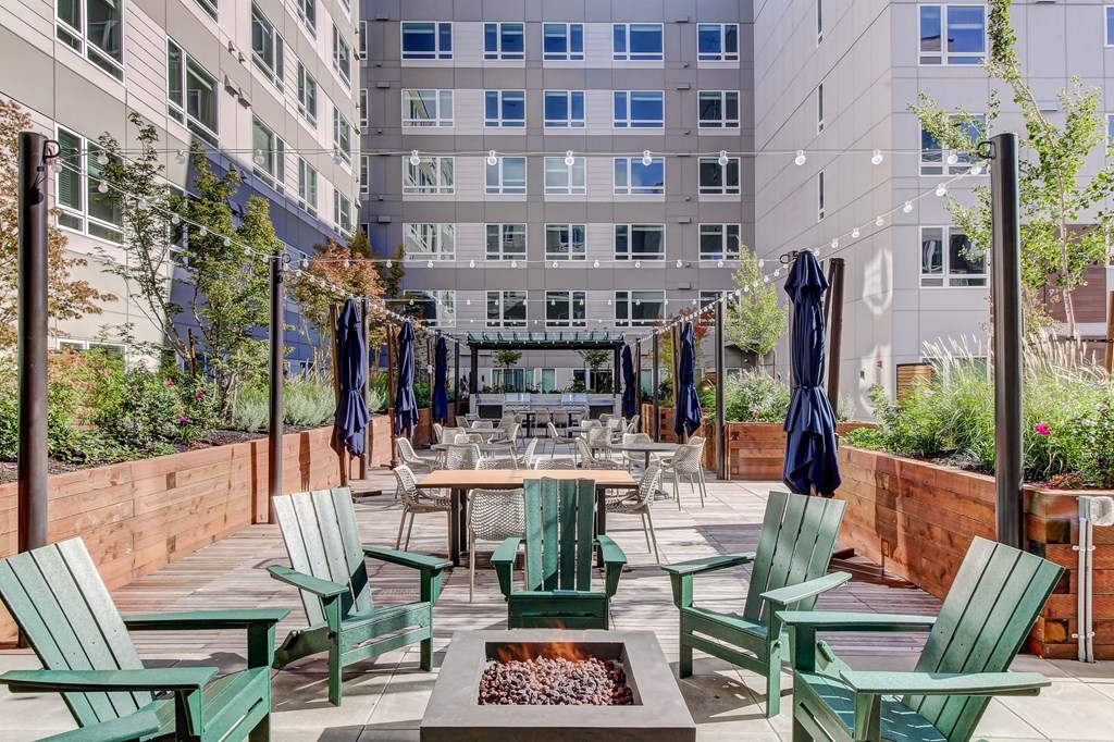 an outdoor patio with tables and chairs and an apartment building in the background