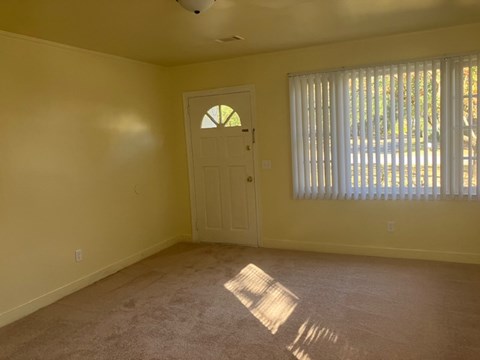 an empty living room with a white door and window