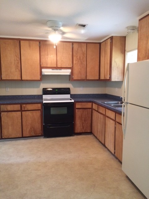 A kitchen with wooden cabinets and a black oven.