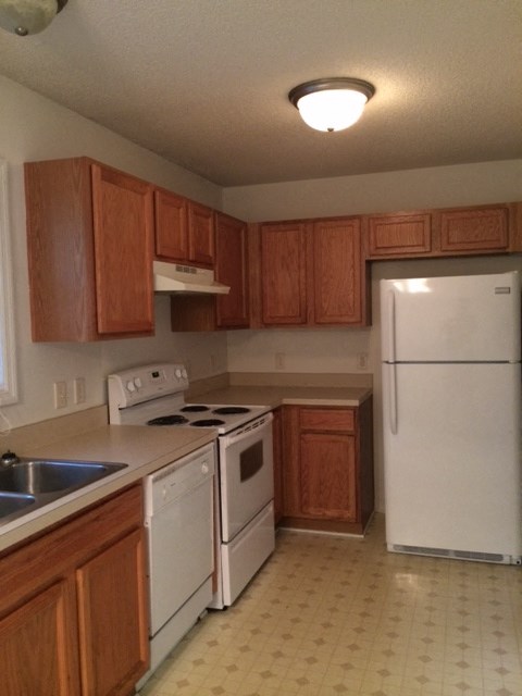 A kitchen with white appliances and wooden cabinets.