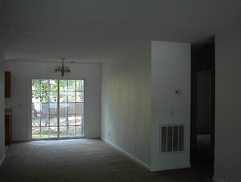 A room with a carpet floor and a sliding glass door leading outside.