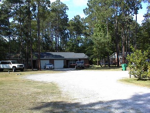 a yard with a house and cars in front of it
