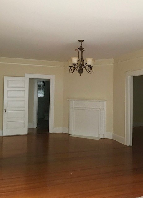 an empty living room with a chandelier and a fireplace