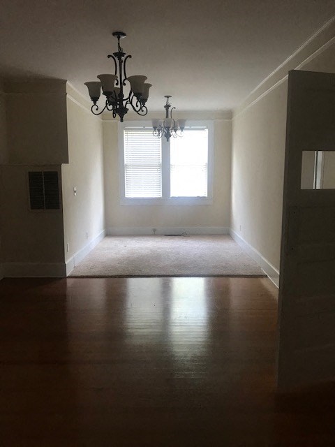 an empty living room with a chandelier and a window