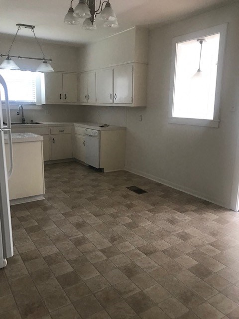 an empty kitchen with white cabinets and a tile floor