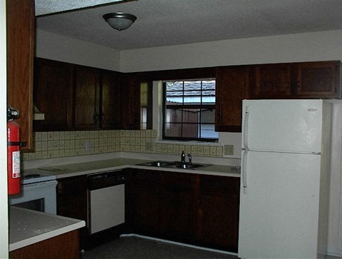 A kitchen with a white refrigerator and brown cabinets.