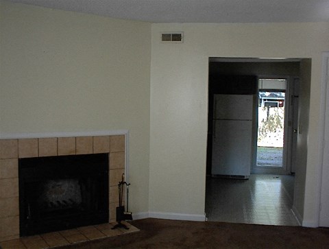A room with a fireplace and a doorway leading to another room.