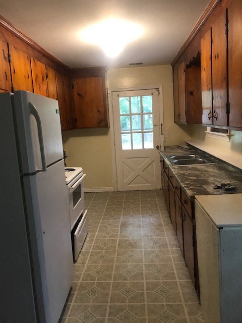 A kitchen with a white fridge and wooden cabinets.