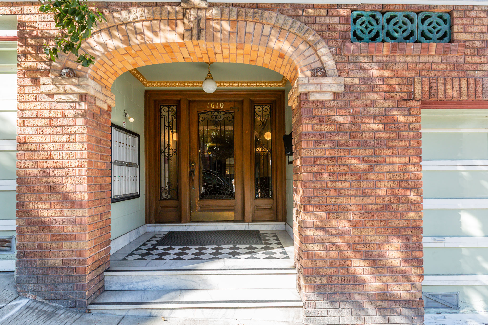A brown door is framed by a brick archway.
