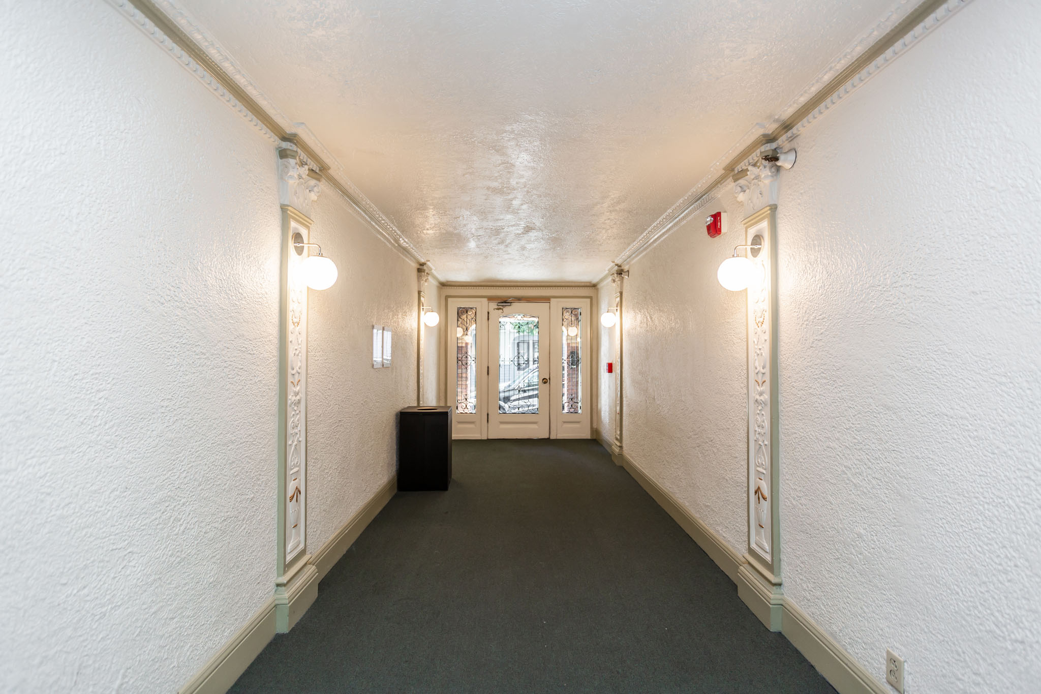 A long hallway with lights on both sides and a door at the end.