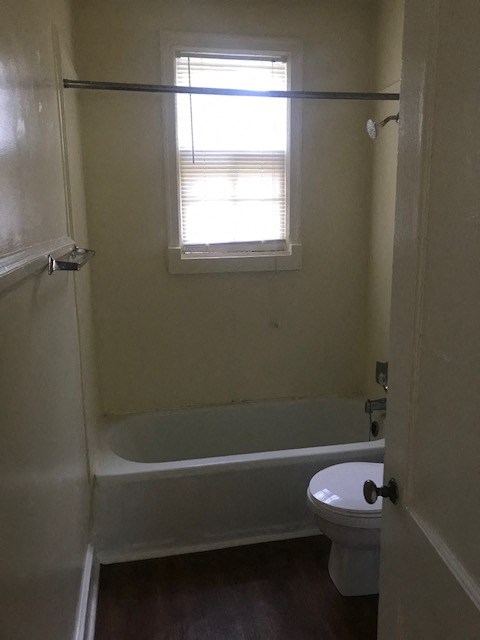 a bathroom with a toilet and a tub and a window