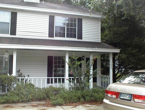 A white house with a car parked in front.