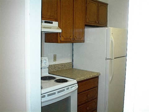 A kitchen with a white refrigerator, white oven, and brown cabinets.