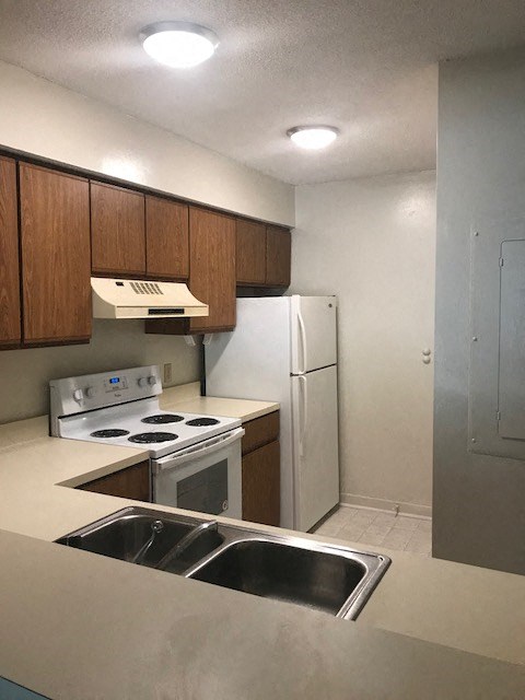 A kitchen with a stove, refrigerator, and sink.