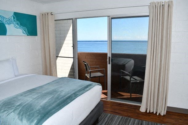 a bedroom with a bed and a balcony overlooking the ocean