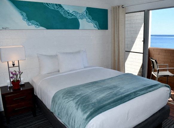 a hotel room with a bed and a view of the ocean