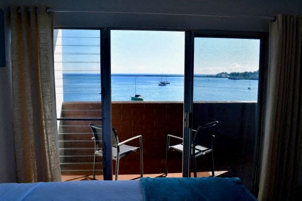 a bedroom with a bed and a balcony overlooking the water