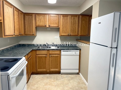 A kitchen with wooden cabinets and a white refrigerator.