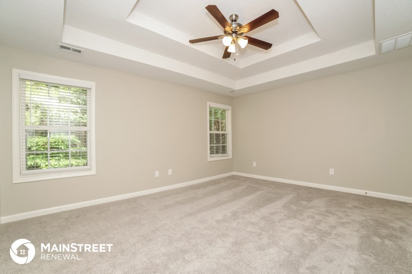 the spacious living room with ceiling fan and carpeting