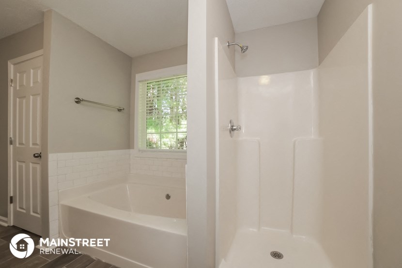 a bathroom with a tub and a shower and a door