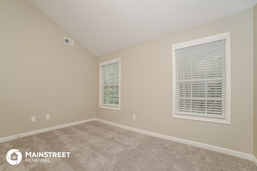 the upstairs bedroom with carpeted flooring and two windows