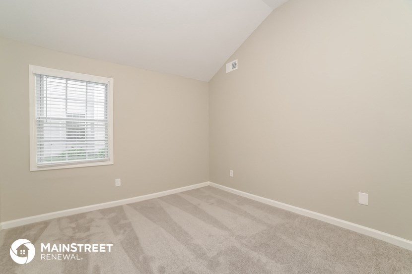 the upstairs bedroom with carpeted flooring and a window