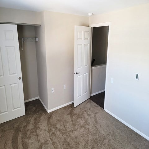 an empty bedroom with a closet and a door to a bathroom