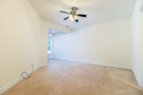 an empty living room with a ceiling fan