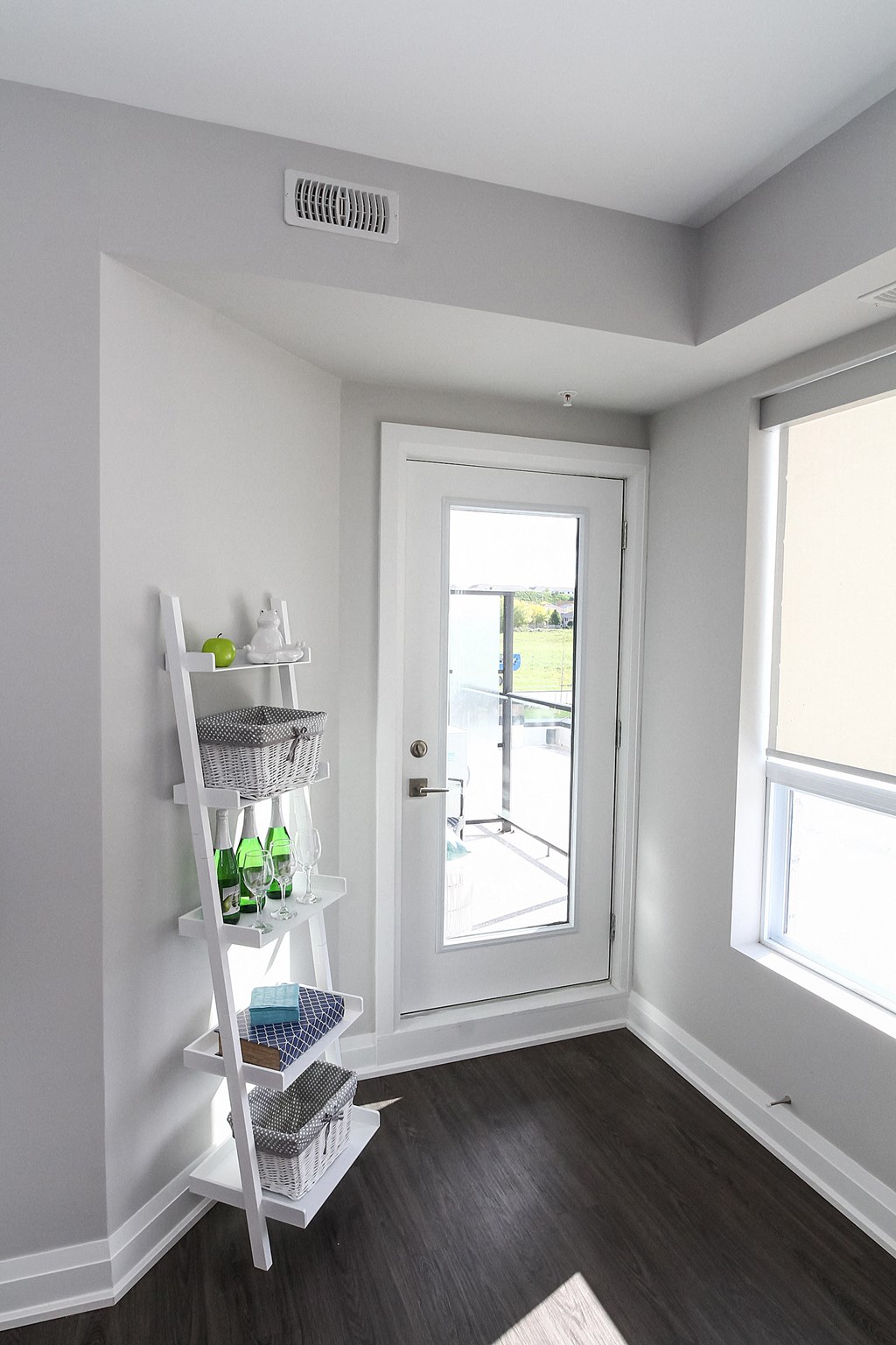 a small room with a white door and a white shelf with bottles on it